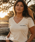 Woman wearing a 'Texas Iberico' t-shirt with a sunset and vintage truck in the background.
