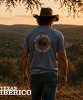 Man wearing a 'Pure Iberico Texas Raised' t-shirt in a desert landscape with 'Texas Iberico' branding.