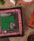 Packaged ground pork from Texas Iberico on a wooden surface with ingredients.